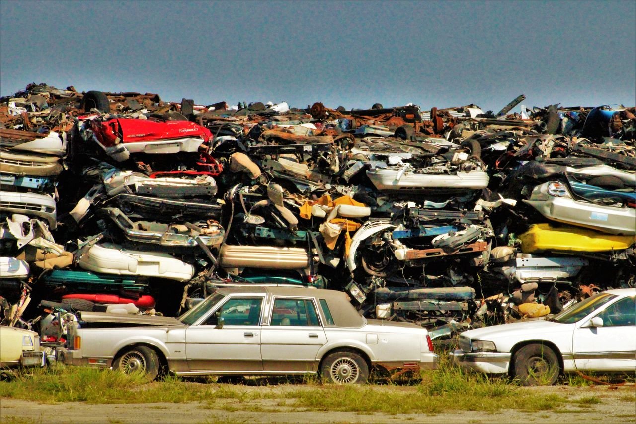 Home A large stack of disposed vehicles in an outdoor junkyard.
